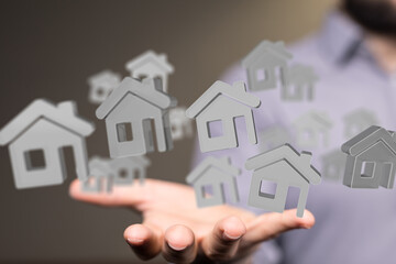 Image of a real estate agent's hand holding multiple digital house icons, representing property...