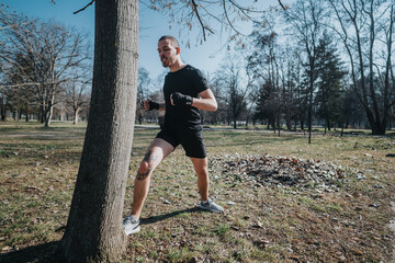 Male athlete stretching near a tree on a sunny day in the park, dressed in sportswear and ready for...