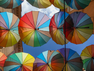 Colorful umbrellas hanging above a narrow street on a sunny day