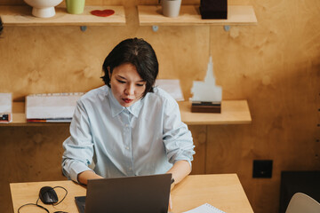 Focused individual seated at a wooden desk in an inviting co working environment, engaging with...