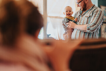 A candid moment of a father cherishing time with his happy baby while the mother observes in the...