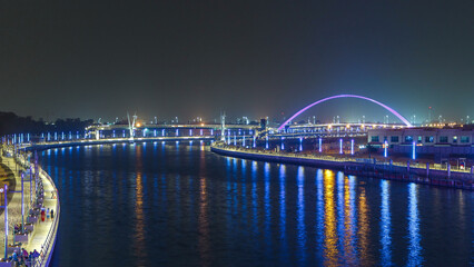 Two bridges over Dubai canal with a boat crossing under them timelapse.