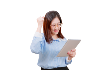 Asian young beautiful woman celebrates while looking at a tablet, smiling with a raised fist and wearing glasses and a striped shirt.