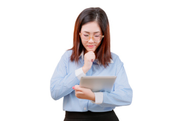 Asian young beautiful woman in glasses thoughtfully uses a tablet, dressed in a blue striped shirt.