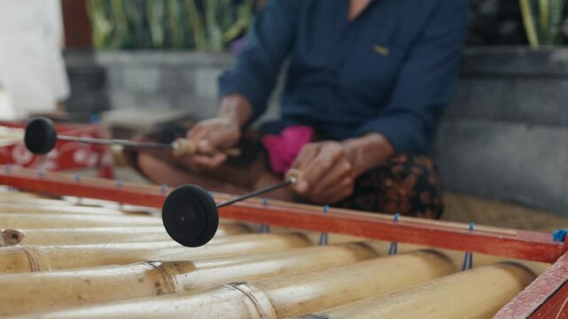 Musician playing traditional balinese gamelan music with rindik instrument