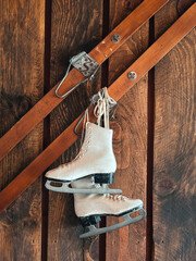 Vintage ice skates hanging on wooden wall with old skis