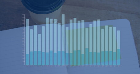 Image of financial graph over notebook on desk