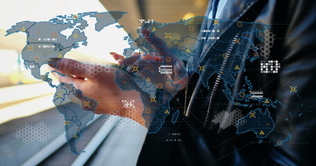 Professional in dark suit jacket tapping smartphone at transit hub, with map overlay and data icons