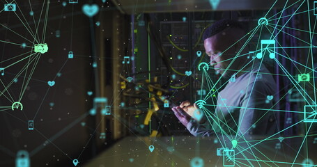 Image of network of connections with icons over african american male server room using tablet