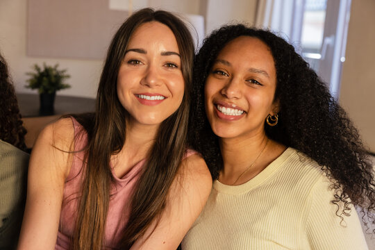 Two friends smiling indoors in natural light