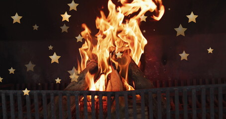 Naklejka premium Image of stars over flames in fireplace