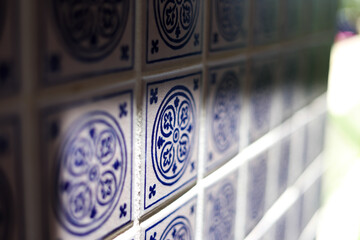 A close up of a blue and white mosiac patterned tile on a wall