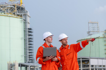 Construction workers conduct safety inspection at industrial plant in sunny afternoon, discussing...