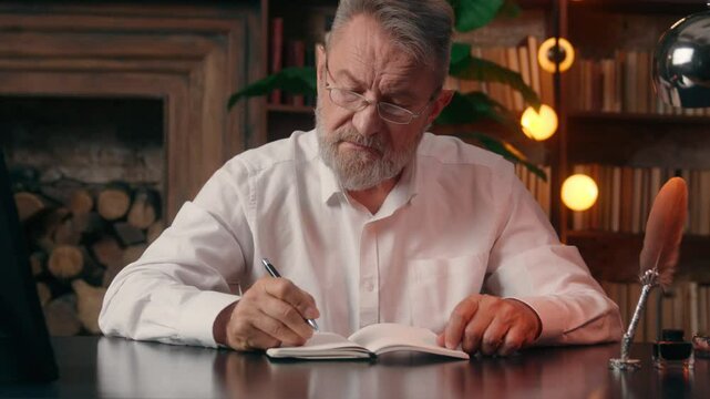 Old Caucasian European man writing notebook male businessman business writer author office indoor professional mature senior inspiration aged grandfather thinking plan decision contemplation create