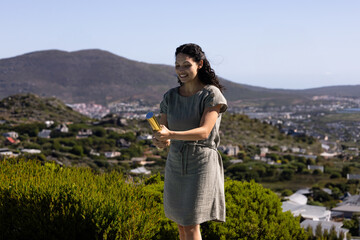 Gold confetti popper is resting among shrubs on hillside overlooking coastal village and horizon