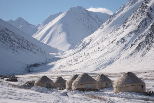 Snowy mountain landscape with traditional yurts in a remote valley during winter sunlight