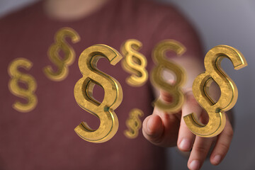 Abstract image of golden paragraph symbols floating above a hand, representing law, legal system,...