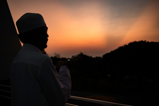 Silhouette Young asian muslim man praying on sunset,Ramadan festival concept