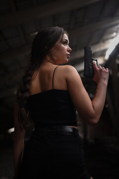 Beautiful woman super agent with pistols in hands posing on abandoned building background..