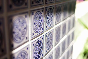 A close up of a blue and white mosiac patterned tile on a wall