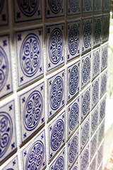 A close up of a blue and white mosiac patterned tile on a wall