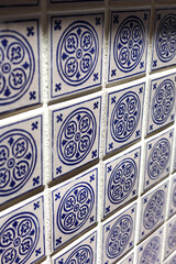 A close up of a blue and white mosiac patterned tile on a wall