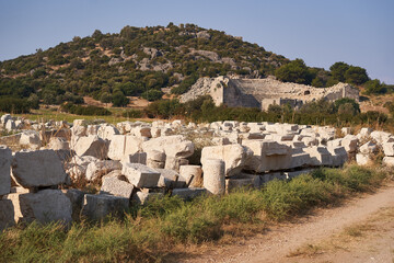 Ancient ruins and amphitheater amidst hilly landscape under clear sky. The ruins of the ancient...