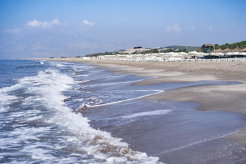 Serene sandy beach with gentle waves and distant umbrellas on a clear day. Patara Beach in Turkey