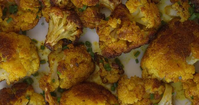 Close-up view of roasted cauliflower with turmeric. Great healthy snack. Zoom in while rotating.
