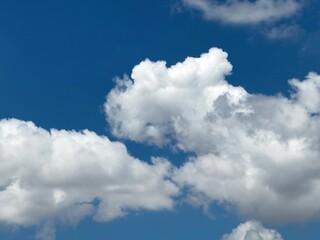 Obraz premium Blue sky with clouds background, sunny day. White and grey fluffy cloudscape