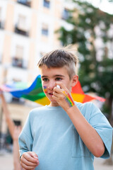 Young boy painting rainbow on his face during pride parade celebrating lgbtq+ community