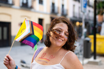 Woman holding intersex-inclusive progress pride flag smiling at pride parade