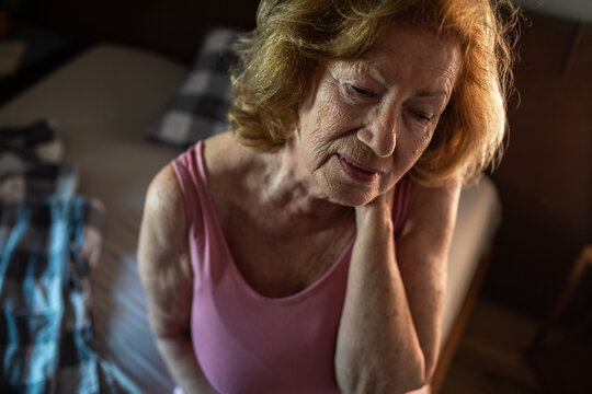Senior woman waking up with neck pain in the morning