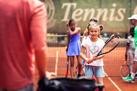 Young girl in tennis court training session learning to play tennis at the club