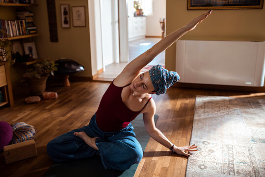 Woman doing yoga stretches at home on a yoga mat