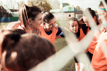 Female soccer team in huddle before game on outdoor field