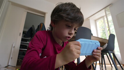 Young boy concentrating, playing with a toy camera indoors, exploring play, holding the camera with...