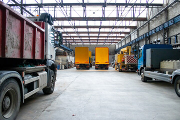 Industrial warehouse with construction materials stacked on pallets, service trucks and forklifts in operation, logistics, storage, and transportation management at a busy construction facility.