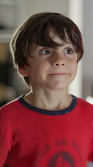 Young boy smiling warmly, looking directly at the camera, cheerful and joyful expression, capturing an innocent and happy moment in a home setting