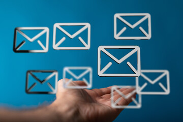 Abstract image of hand holding email icons, representing digital communication and online messaging.