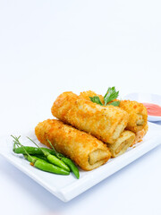 Indonesian crispy rissoles , served on a white plate with spicy red chili sauce and green chili on a white background. Perfect photo of a traditional snack.