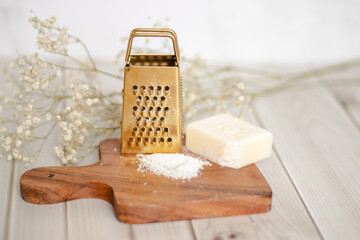 Aromatherapy wax melt block with grated flakes on a wooden board, styled with candle and flowers. Perfect for home fragrance and relaxation visuals.