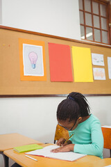 Notebook is lying on desk in classroom as pencil is resting on green book near window