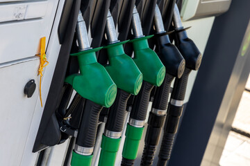 Close-up of fuel pump nozzles at station. Green and black fuel nozzles aligned at a modern gas...