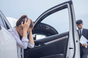 An anxious businesswoman sits alone next to her broken car, distressed and frustrated, and calls for urgent help during a transportation crisis.