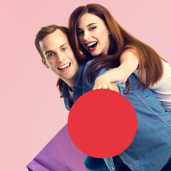 Holiday sales actions, rebates offers, price discounts, ad concept image - happy expressive young couple man and woman with shopping bag, hold red сircle sign board. Isolated pink background. Square