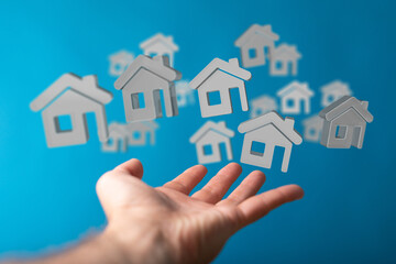 Image of a hand reaching for multiple small house icons, symbolizing real estate, property, and...