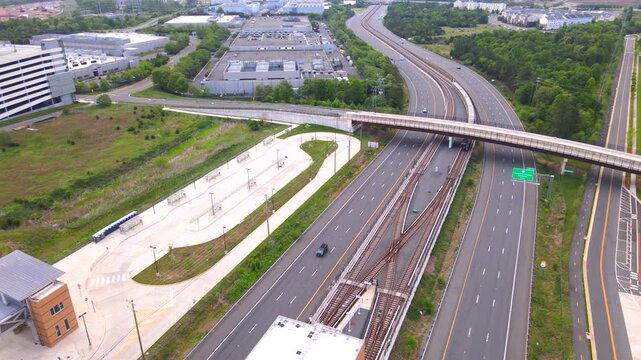 Metro train leaves the elevated Metro station toward Washington, DC. panoramic View from a drone. Highways, parks and bus stops
