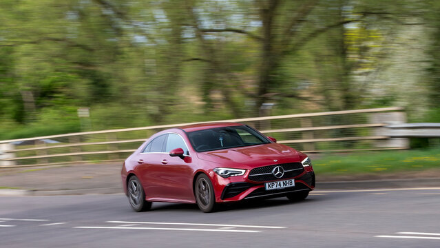 Milton Keynes,UK - Apr. 14th 2025:   2024 red Mercedes Benz CLA 200 amg line hybrid electric car driving on a British  road