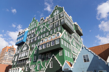 Unique and colorful hotel building resembling stacked traditional Dutch houses in Zaandam the Netherlands, set against a bright blue sky, showcasing innovative architecture.
